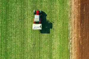 Agricultural tractor fertilizing wheat crop field with NPK