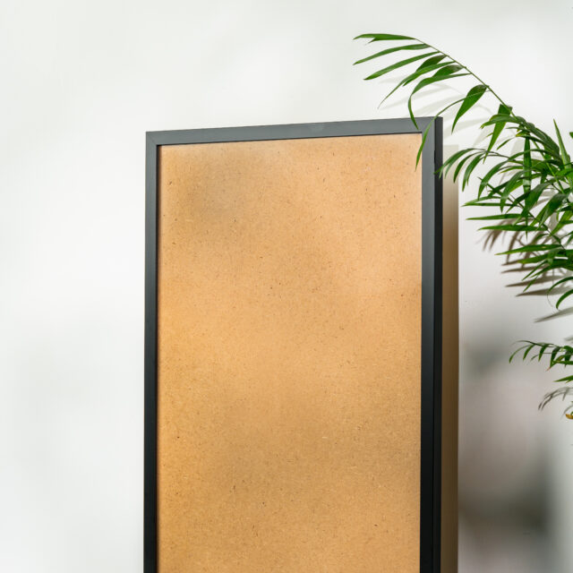 Black wooden photo frame and plant on gray background