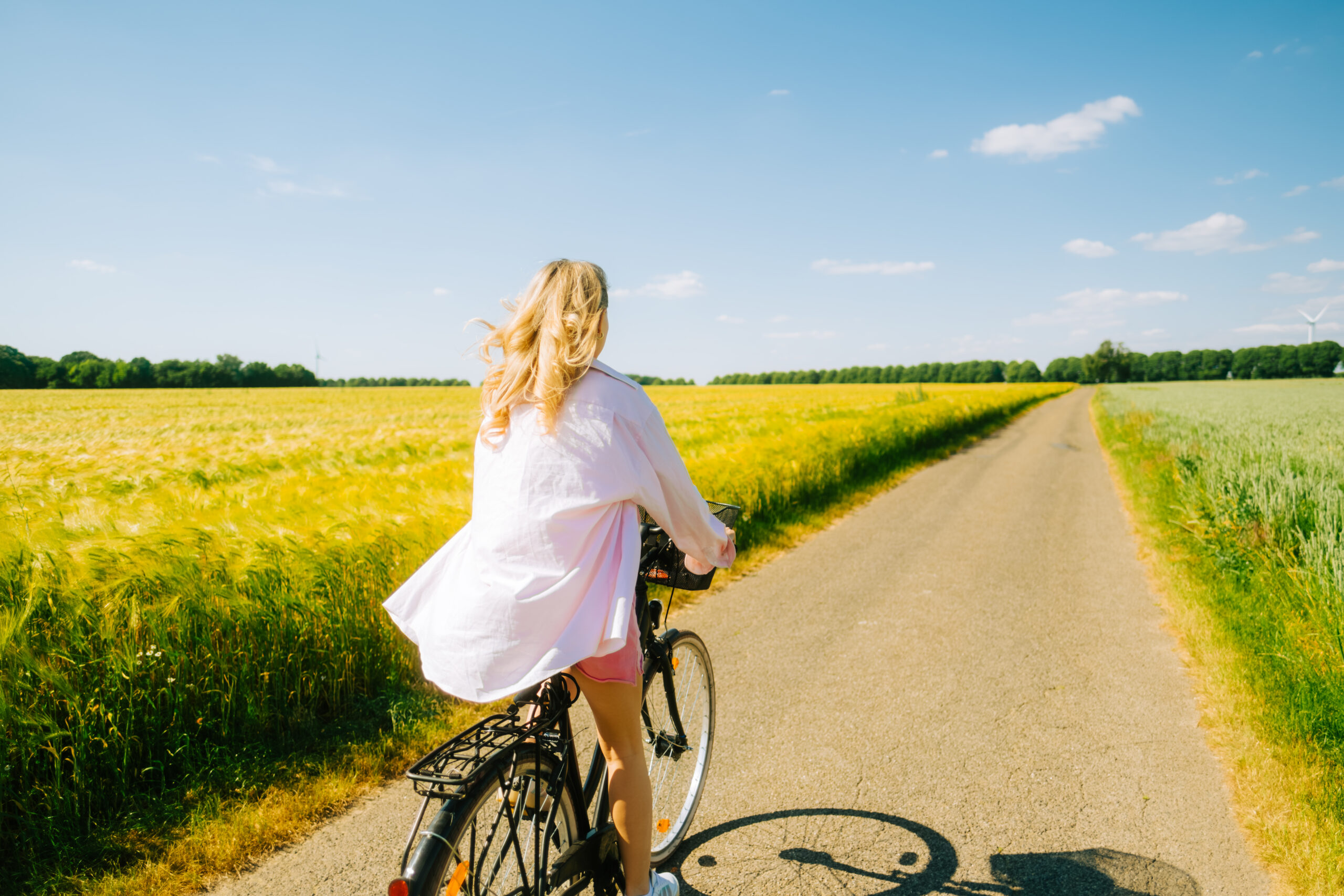 lyshåret kvinde på cykel ved en mark på en sommerdag